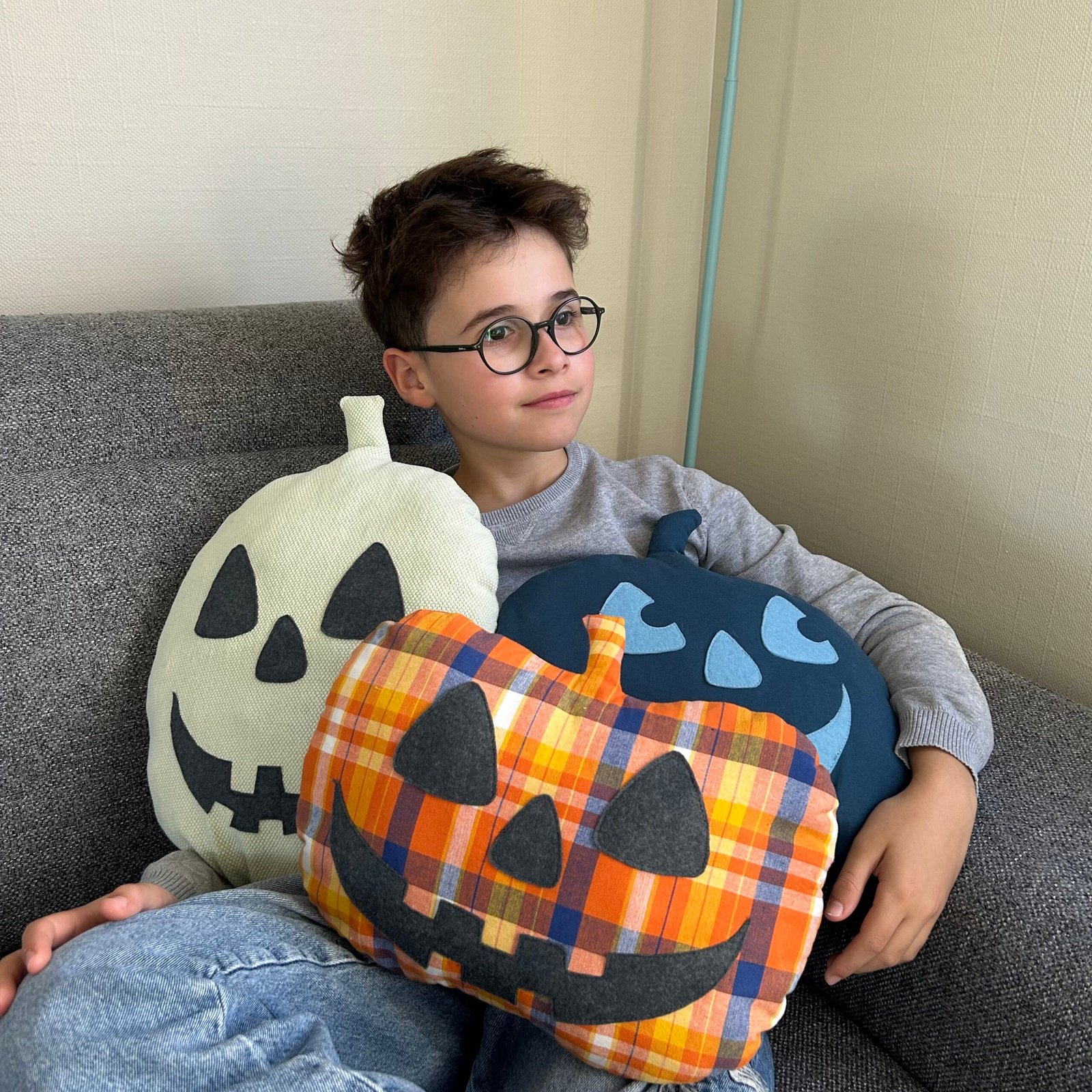Trois coussins citrouilles décoratifs tenus dans les bras par un enfant