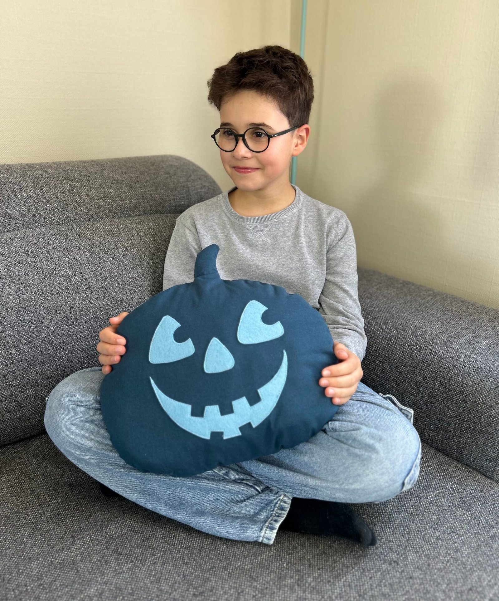 Troisième coussin citrouille décoratif tenu dans les bras par un enfant