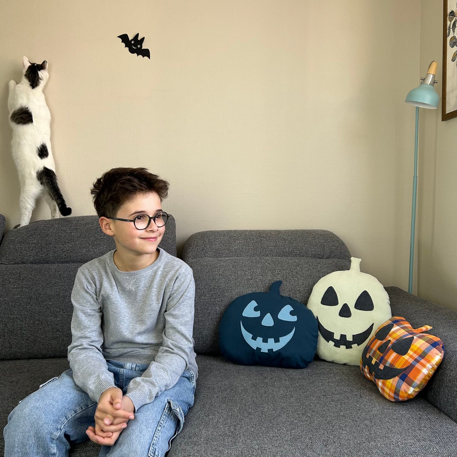 Trois coussins citrouilles cousus main à côté d'un enfant avec un chat qui joue en arrière-plan